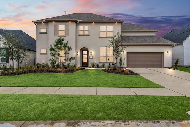 view of front facade featuring a garage, a yard, concrete driveway, and stucco siding