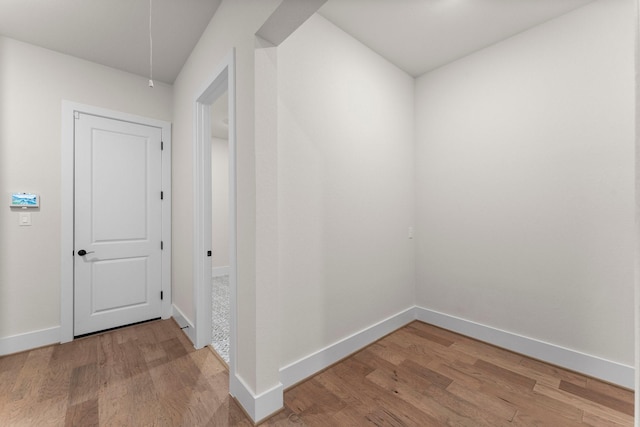 hallway with baseboards, attic access, and light wood-style floors