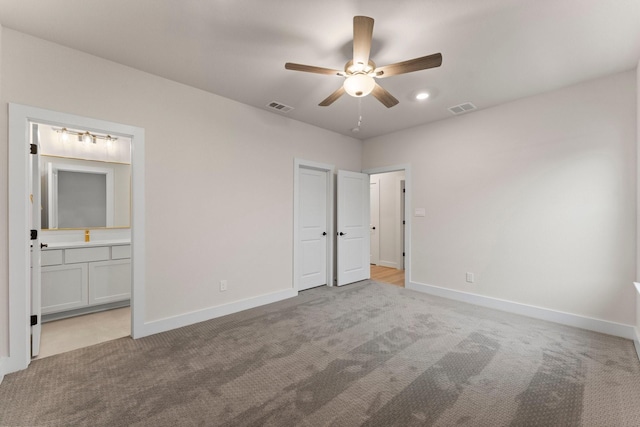 unfurnished bedroom featuring ensuite bathroom, light colored carpet, and ceiling fan