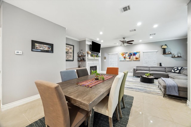 tiled dining room featuring ceiling fan and crown molding