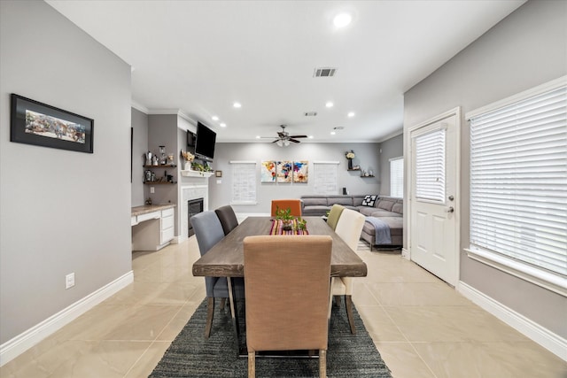 tiled dining space featuring ceiling fan and ornamental molding