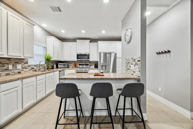 kitchen with light tile patterned floors, light stone countertops, sink, and stainless steel appliances