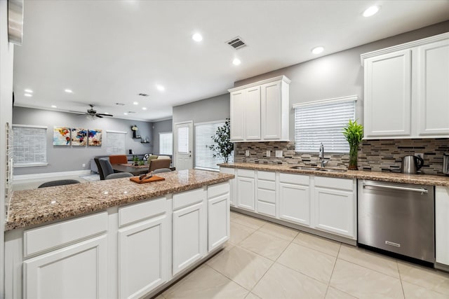 kitchen with ceiling fan, light stone countertops, stainless steel dishwasher, white cabinets, and sink