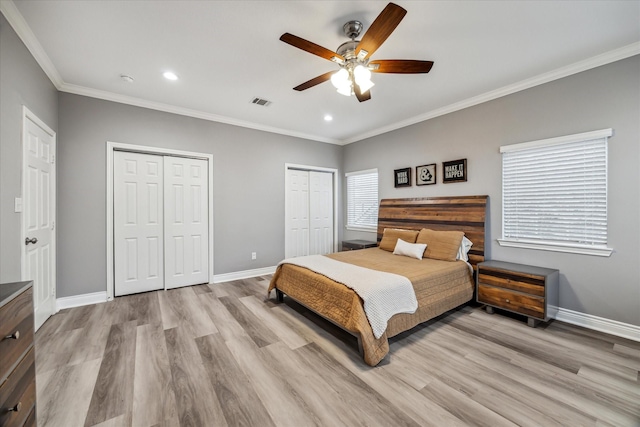 bedroom with light wood-type flooring, ceiling fan, ornamental molding, and multiple closets