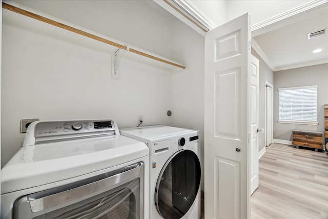 laundry room with crown molding, washer and clothes dryer, and light hardwood / wood-style floors