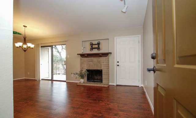 unfurnished living room with dark wood-type flooring, a chandelier, and a fireplace