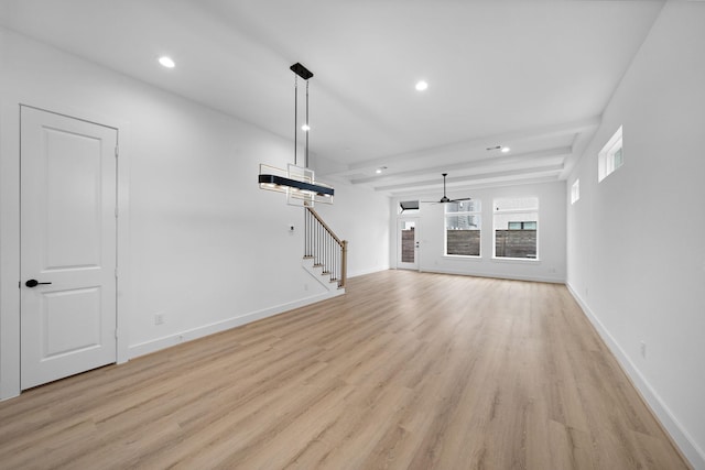 unfurnished living room featuring ceiling fan, beamed ceiling, and light wood-type flooring