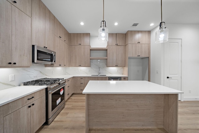 kitchen with decorative light fixtures, appliances with stainless steel finishes, sink, and light hardwood / wood-style floors