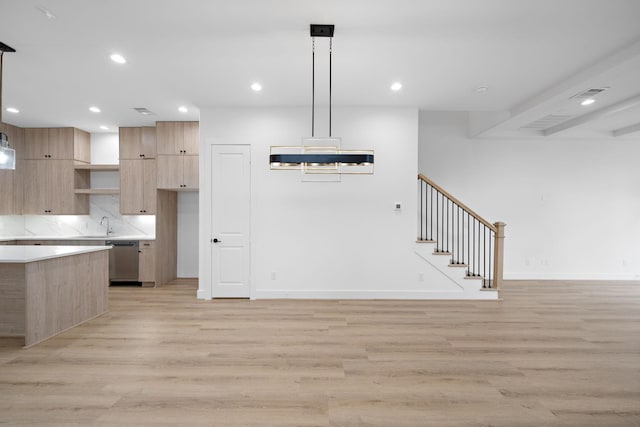 kitchen with decorative light fixtures, stainless steel dishwasher, and light wood-type flooring