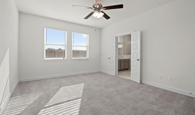 unfurnished bedroom featuring ceiling fan, baseboards, ensuite bathroom, and light colored carpet