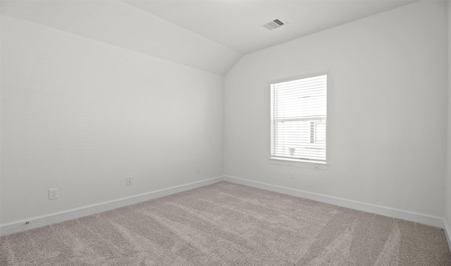 unfurnished room with visible vents, vaulted ceiling, light carpet, and baseboards