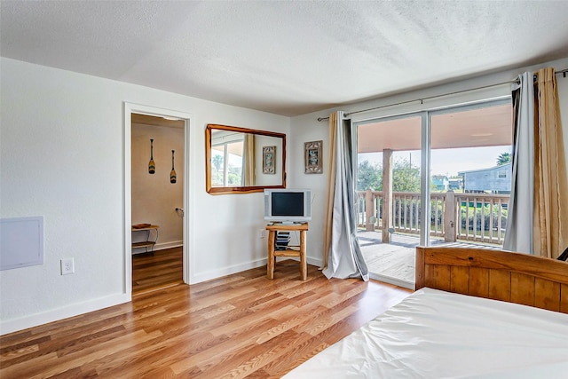 unfurnished bedroom with light wood-type flooring, access to exterior, a textured ceiling, and multiple windows