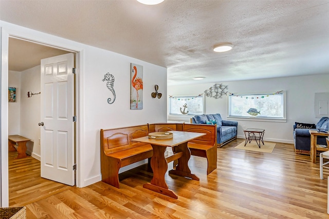 dining space with a textured ceiling and light hardwood / wood-style flooring