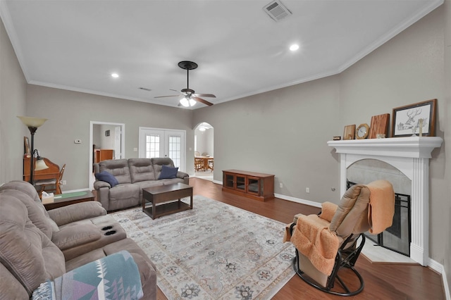 living room with ceiling fan, french doors, wood-type flooring, ornamental molding, and a tile fireplace