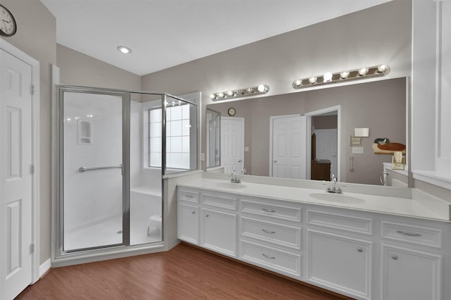 bathroom with wood-type flooring, walk in shower, lofted ceiling, and vanity