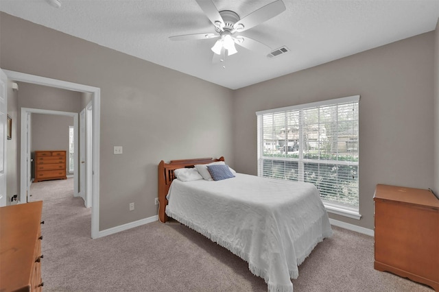 carpeted bedroom featuring a textured ceiling, ceiling fan, and multiple windows