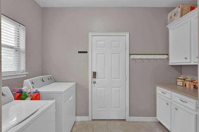 washroom with light tile patterned flooring, plenty of natural light, independent washer and dryer, and cabinets