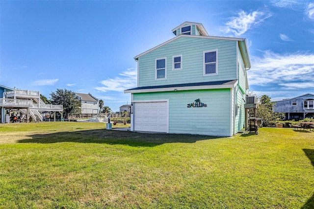 rear view of property featuring a garage and a lawn