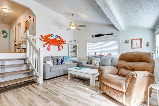 living room with a textured ceiling, ceiling fan, light hardwood / wood-style floors, and vaulted ceiling with beams