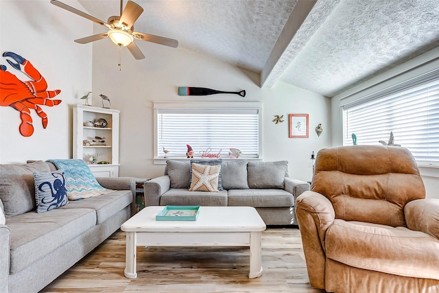 living room with ceiling fan, a textured ceiling, light hardwood / wood-style flooring, and lofted ceiling with beams