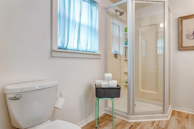 bathroom featuring toilet, plenty of natural light, hardwood / wood-style flooring, and an enclosed shower