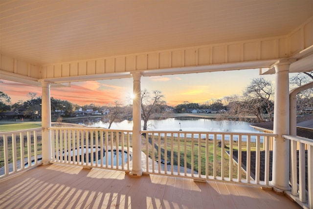 deck at dusk featuring a water view