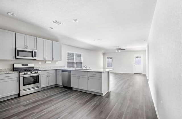 kitchen featuring kitchen peninsula, ceiling fan, appliances with stainless steel finishes, dark hardwood / wood-style floors, and sink