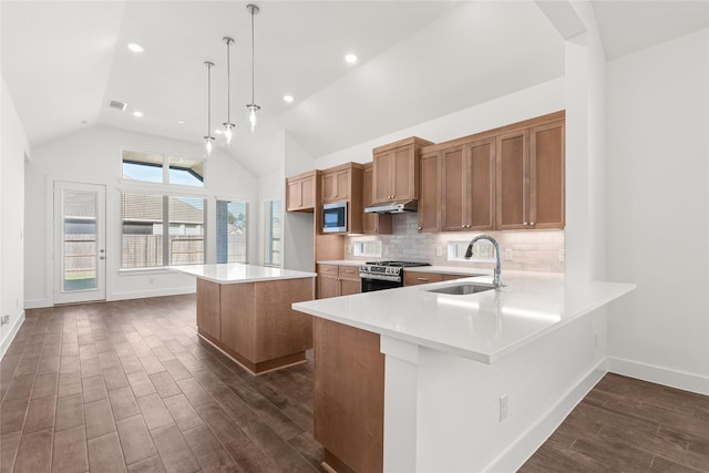 kitchen with a center island, decorative light fixtures, stainless steel appliances, sink, and high vaulted ceiling