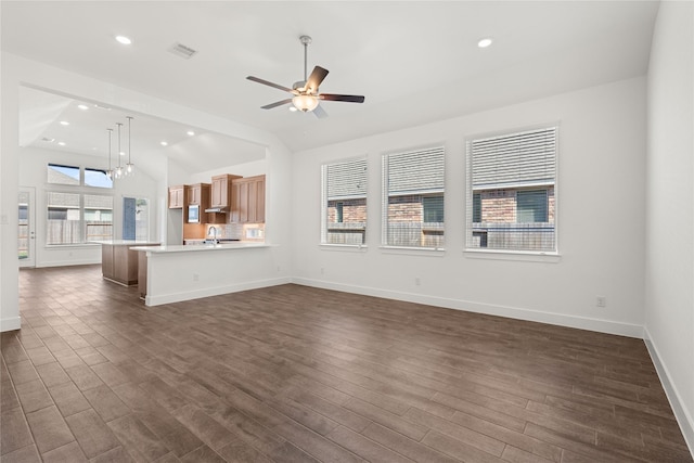 unfurnished living room featuring dark hardwood / wood-style flooring, lofted ceiling, ceiling fan with notable chandelier, and sink