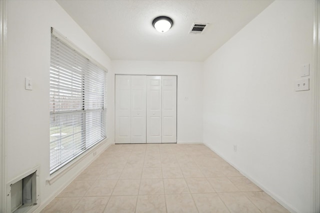 unfurnished bedroom with a textured ceiling, a closet, and light tile patterned flooring