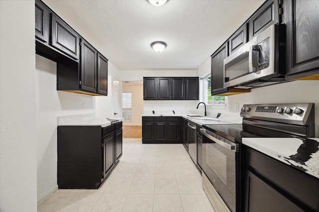 kitchen featuring light tile patterned floors, sink, a textured ceiling, and appliances with stainless steel finishes