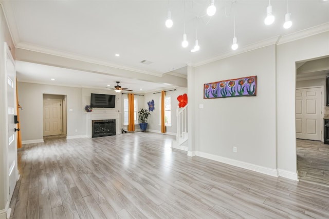 unfurnished living room with ceiling fan, ornamental molding, and light wood-type flooring