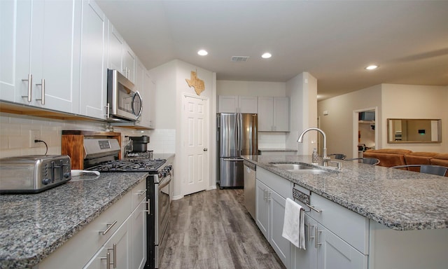 kitchen with sink, white cabinets, stainless steel appliances, and a kitchen island with sink