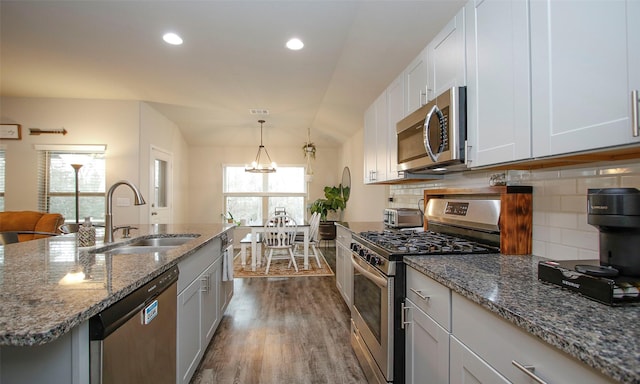 kitchen with backsplash, sink, white cabinetry, appliances with stainless steel finishes, and an island with sink