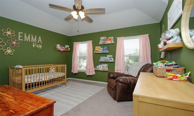 carpeted bedroom featuring ceiling fan, a nursery area, vaulted ceiling, and multiple windows