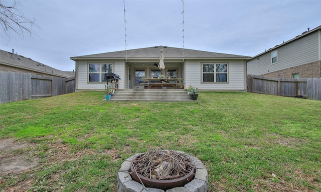 back of property featuring a lawn, an outdoor fire pit, ceiling fan, and a deck