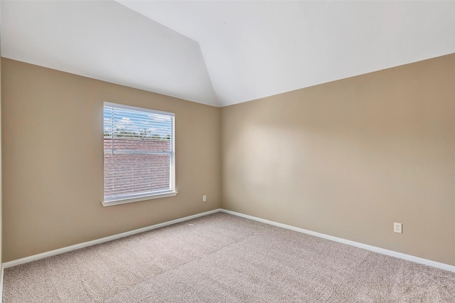 carpeted spare room featuring vaulted ceiling