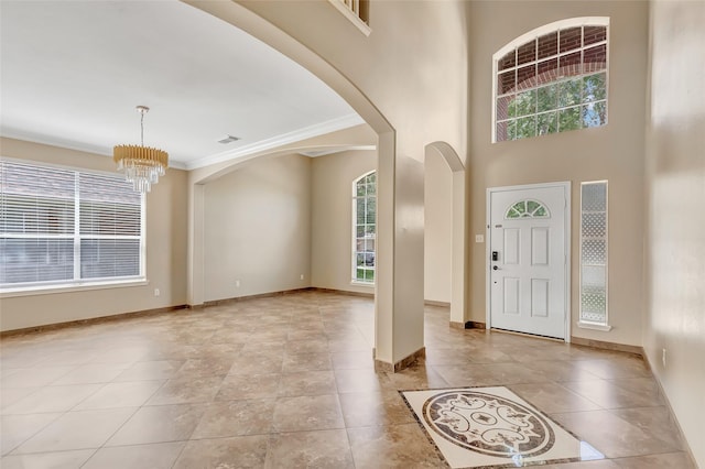 tiled entryway featuring ornamental molding and a chandelier