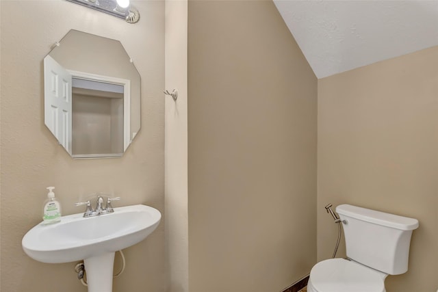 bathroom with toilet, vaulted ceiling, and a textured ceiling