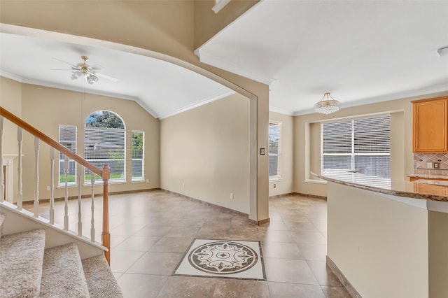 entryway with ceiling fan with notable chandelier, ornamental molding, lofted ceiling, and light tile patterned flooring