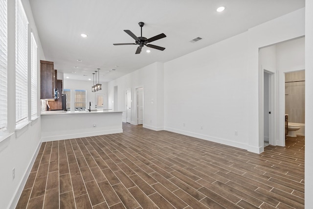 21514 Witham Promenade Ln, Magnolia, TX 77355 - unfurnished living room featuring dark wood-style floors, visible vents, ceiling fan with notable chandelier, and recessed lighting