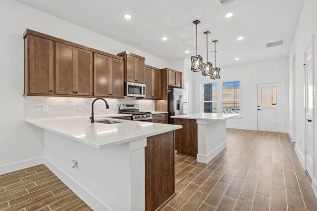 21514 Witham Promenade Ln, Magnolia, TX 77355 - kitchen featuring a sink, decorative backsplash, stainless steel appliances, dark wood-type flooring, and light countertops