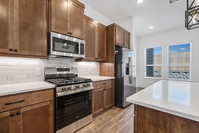 21514 Witham Promenade Ln, Magnolia, TX 77355 - kitchen with light countertops, wood finished floors, stainless steel appliances, and decorative backsplash