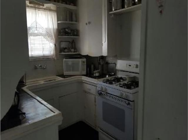 kitchen featuring white cabinetry and white range with gas stovetop