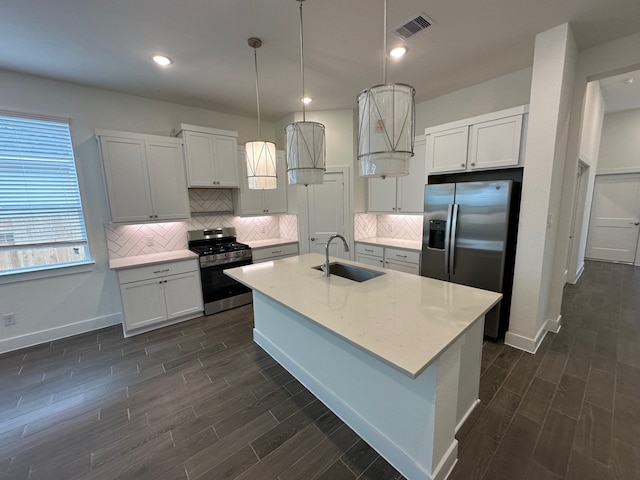 kitchen featuring visible vents, wood finish floors, decorative backsplash, stainless steel appliances, and a sink