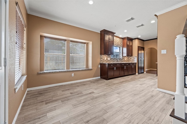 kitchen featuring light hardwood / wood-style floors, backsplash, dark brown cabinets, crown molding, and sink