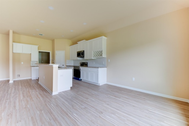 kitchen featuring white cabinets, appliances with stainless steel finishes, light hardwood / wood-style flooring, backsplash, and a center island with sink