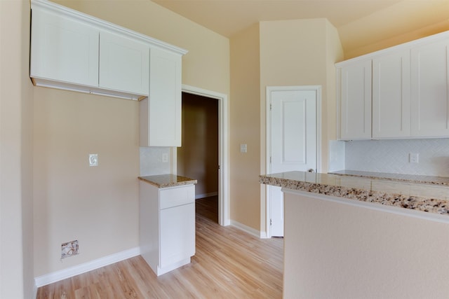 kitchen featuring light stone counters, white cabinetry, light hardwood / wood-style flooring, and tasteful backsplash