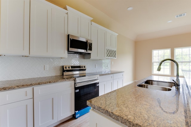 kitchen with light stone countertops, sink, stainless steel appliances, and white cabinetry