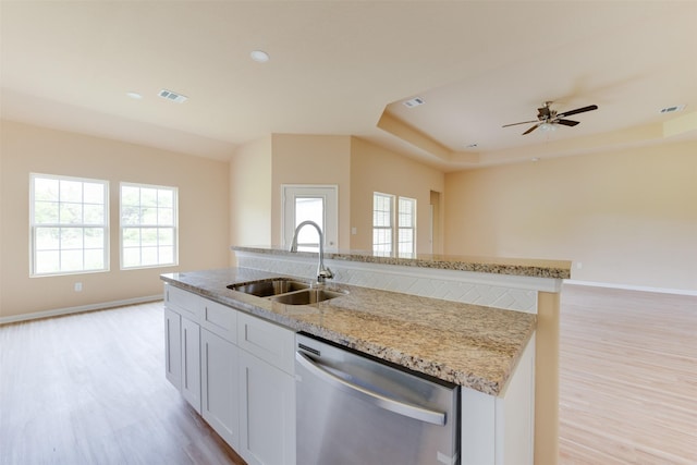 kitchen featuring light stone countertops, white cabinets, sink, stainless steel dishwasher, and light hardwood / wood-style flooring